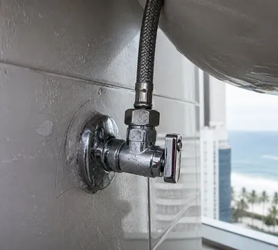 Llave de paso y flexo bajo un lavabo durante una reparación de fontanería en Cabo de Palos